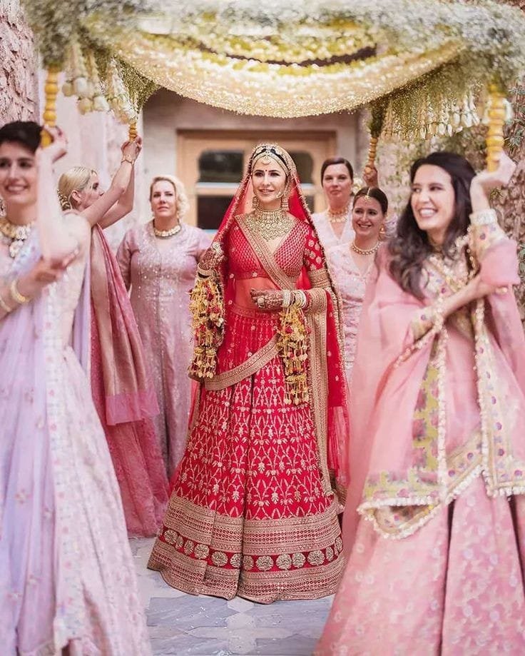 Bride smiling during entry with bridesmaids holding dupatta